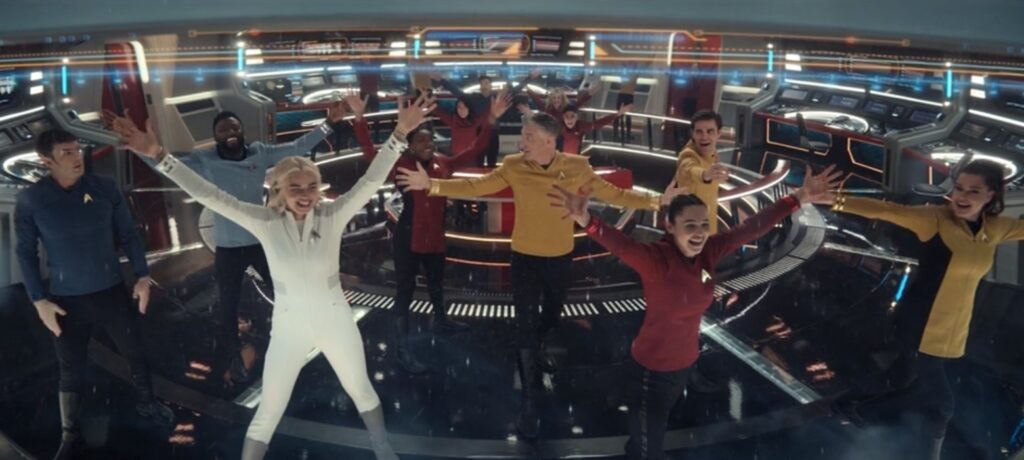 The entire cast of Strange New Worlds poses on the bridge with arms outstretched (except Spock), as if seen from behind the bridge viewscreen.