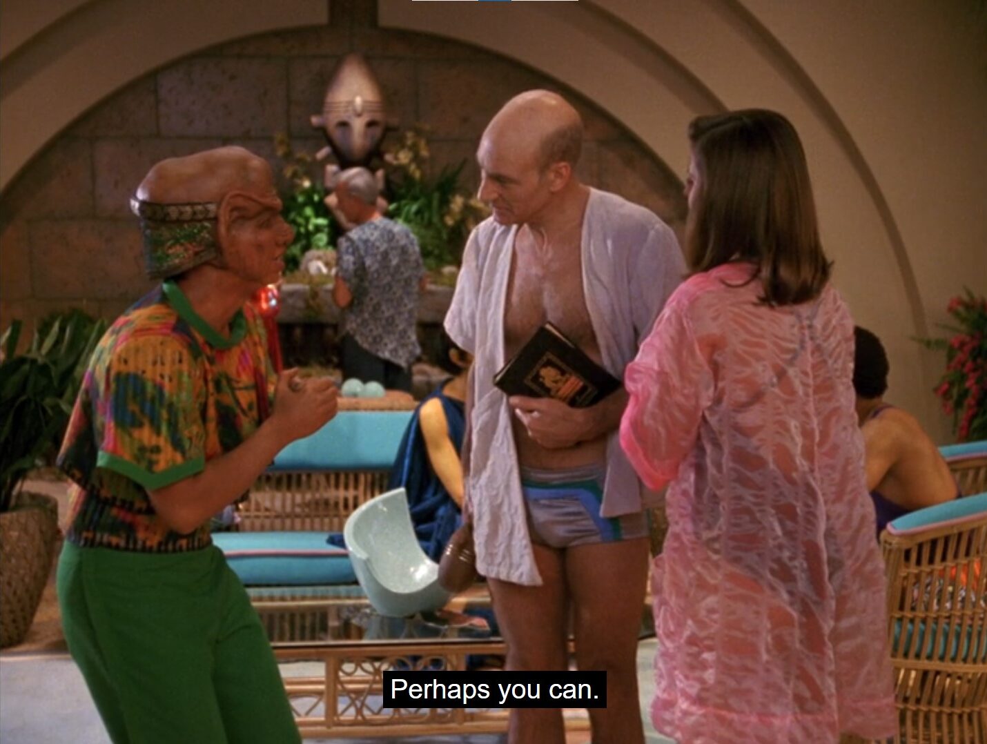 A large-eared Ferengi wearing flashy clothes hunches and clasps his hands while confronted by Picard in tiny shorts and Vash in a gauzy robe.